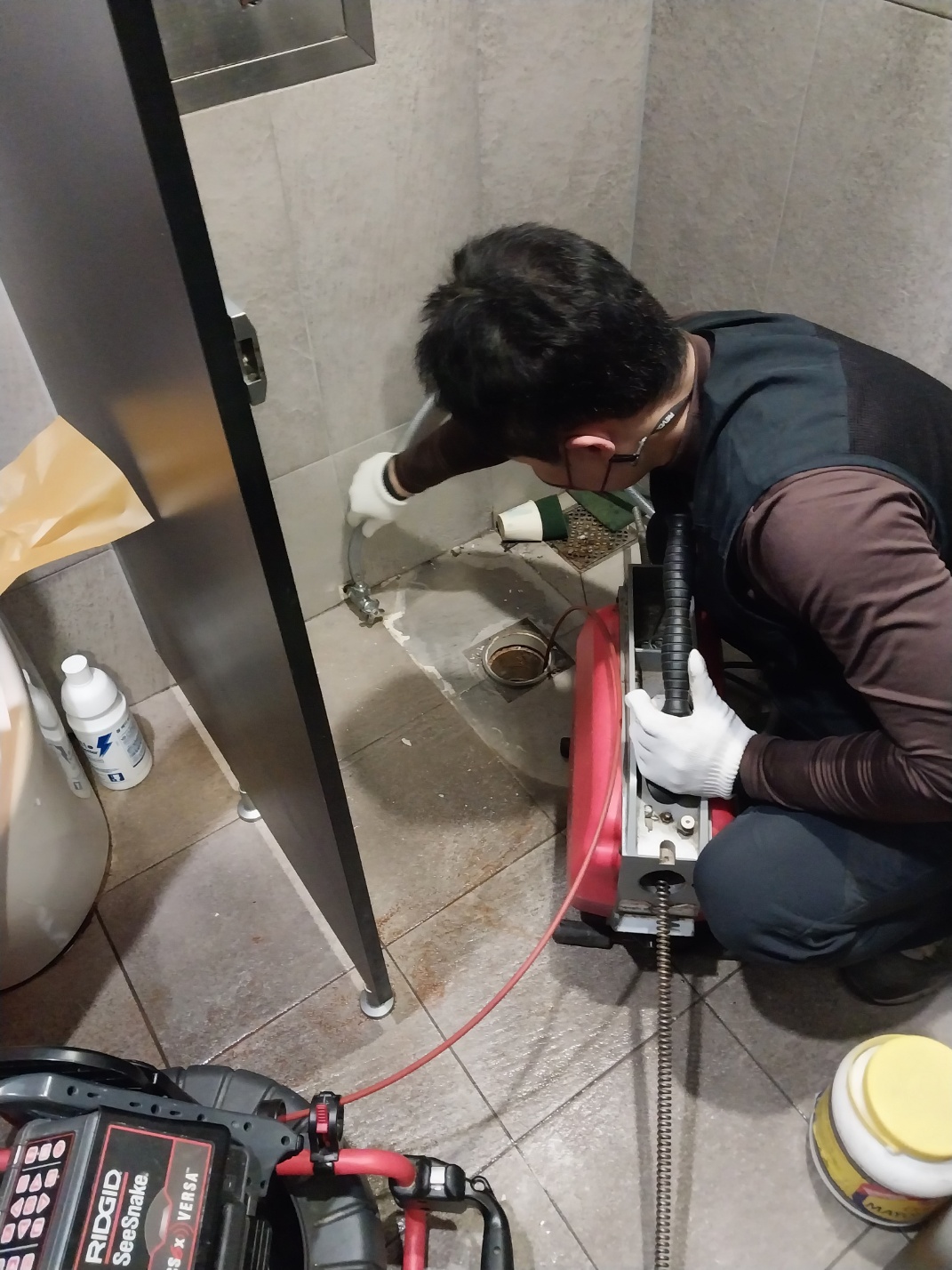 작업자가 변기를 분리한 뒤 전동 스프링 장비로 바닥 오수관을 작업하는 모습